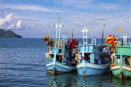 Three small thai fishing boat anchor at island on day blue skyの写真素材