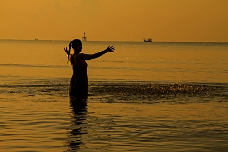 Happy lady relax with shunshine and silhouette on beach in the morningの写真素材