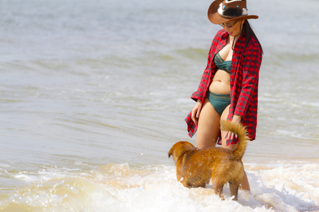 Woman happy outdoor with dog and hat on beach at Bang Beot beach, Chumphon Province Thailandの写真素材