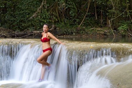 Woman with red bikini relax at Erawan Waterfall and natural in Kanchanaburi province Thailand.Erawan Waterfall Is a beautiful and famous water fall.の写真素材