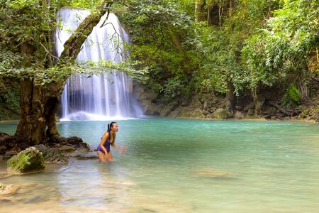 Woman with swimsuit stand enjoy at Erawan Waterfall and  natural in Kanchanaburi province Thailand.
Erawan Waterfall  Is a beautiful and famous water fall.の写真素材