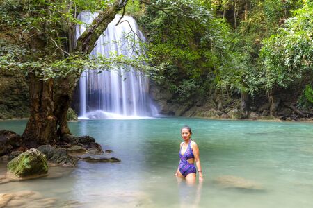 Woman with swimsuit stand smile in water at Erawan Waterfall and  natural in Kanchanaburi province Thailand.
Erawan Waterfall  Is a beautiful and famous water fall.の写真素材