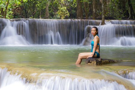 Woman in blue swimsuit at Huai Mae Khamin waterfall and natural in Kanchanaburi province Thailand.Huai Mae Khamin waterfall is in rain forest and tree green.の写真素材