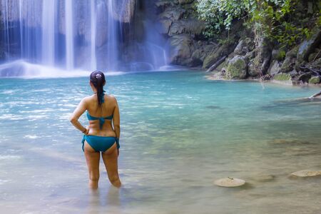 Woman in blue swimsuit look water at  Erawan Waterfall and natural in Kanchanaburi province Thailand.
Erawan Waterfall Is a beautiful and famous water fallの写真素材