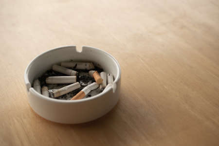 The bunrt cigarettes in the tray on the table , Unhealthy idea , smoking concept.