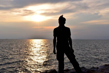 The man standing on the coast of sea to watch the sunsetの写真素材