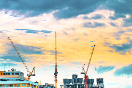 Bird view over cityscape and construction site including several cranes working on a building complex, with sun and clouds in the morning.Copy space.Bangkok.Pastel toneの写真素材