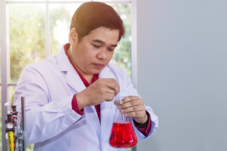 Portrait man of mature scientist in a white coat holding test tube at laboratory.の写真素材