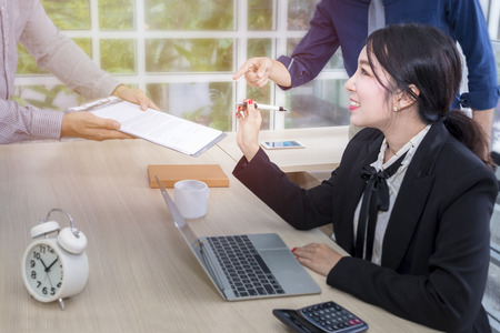 Young businesswoman sign a document and meeting with business teamwork at office.Holding pen in hand.Copy space.の写真素材