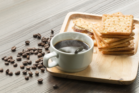 Black coffee,cracker and coffee bean on wood with warm morning light.Copy space.の写真素材
