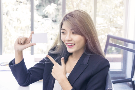 Young businesswoman smiling and thinking about project work at office.Lady holding credit card.Copy space.の写真素材