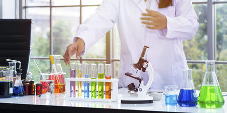 Color water in test tube and beaker near microscope at laboratory.Copy space on white science lab.の写真素材