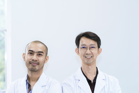 Senior handsome researcher and team smile meeting about research at laboratory.Doctor in white suit .Copy space.の写真素材