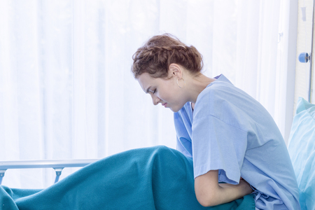 Beautiful young woman patient with period pain on hospital bed room.Copy space.の写真素材