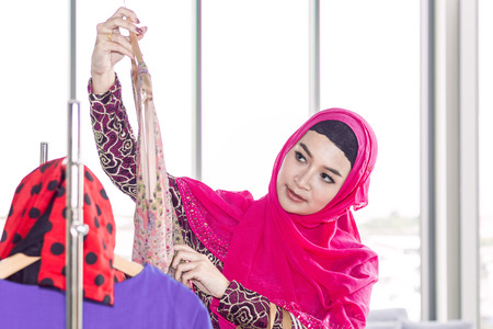Young beautiful woman with shopping bags enjoying in shopping at clothing store.Lady in hijab choosing clothes. Copy space.の写真素材
