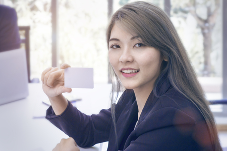 Young businesswoman smiling and thinking about project work at office.Lady holding credit card.Copy space.の写真素材