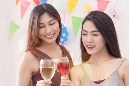Young beautiful women celebrate holiday party and dancing on white wall.Best friends wearing dress posing ,having fun,drinking alcohol cocktails and champagne.Pastel tone.の写真素材
