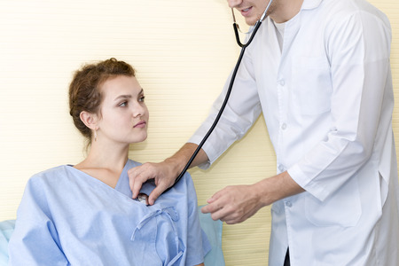 Medical professionals caucasian man examining patient with stethoscope in hospital, doctor using stethoscope to exam young woman check up.Close up.の写真素材