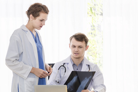 Medical professionals caucasian man holding xray and conversation about patient with young doctor woman.Stressed and worry doctor gives bad news.Close up and copy space.の写真素材