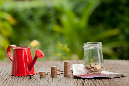 Money and money jar with watering can and cash, Saving money concept, financial savings to buy a house,trees growing in a sequence of germination on piles of coins, Growth, business, money.の写真素材