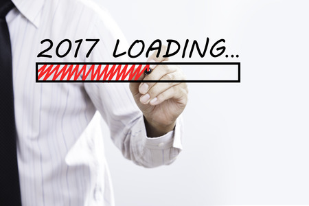 Businessman hand writing New Year 2017 Loading  with red marker on transparent wipe board, business...