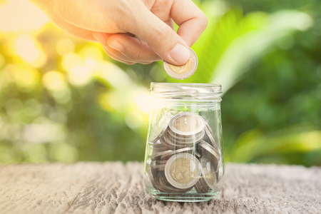 women hand putting money coin in jar. concept saving money  growing business