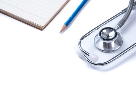 Medical concept : stethoscope on note book and pencil with white backgroundの写真素材