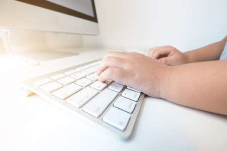 boy hands are typing on computer keyboard. Side view