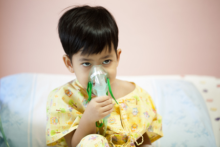 little boy wearing oxygen mask in hospital ward, Sitting on the bed patientsの写真素材