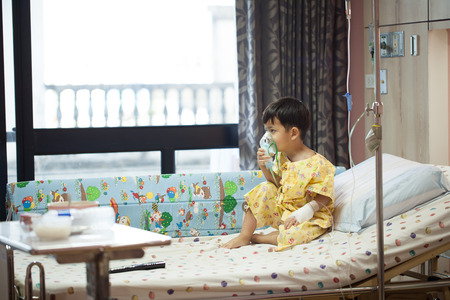 little boy wearing oxygen mask in hospital ward, Sitting on the bed patientsの写真素材