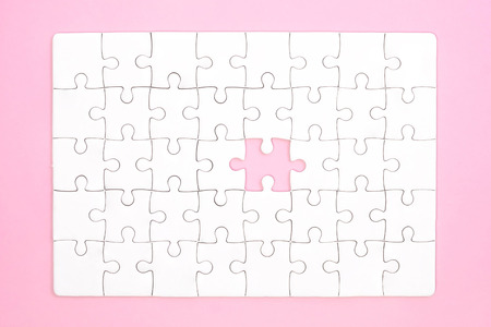 White jigsaw puzzle on pink backgroundの写真素材