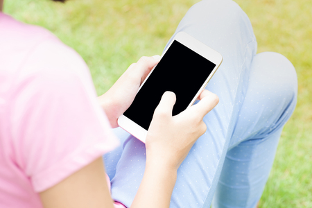 Young and attractive woman using modern smartphone with blank screen and sunlightの写真素材
