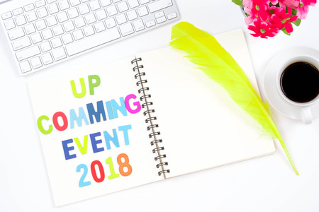 Top viwe of modern workplace with office supplies, yellow feather, a cup of coffee and keyboard on white background. Flat lay design and up comming event 2018 wordsの写真素材