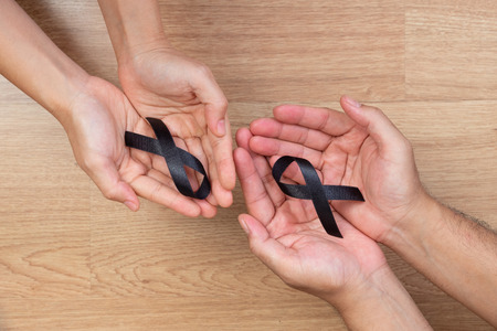 Man hands holding a black ribbon on wooden backgroundの写真素材