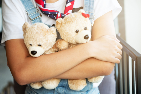Girl hugging two teddy bears in a coffee shop. Valentine's Day, love concept.の写真素材