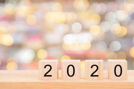 Happy new year 2020 text on wooden cubes on wooden pine table and blur light bokeh background....
