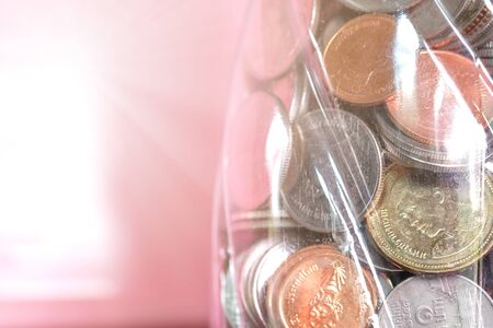 Coins in plastic bottle piggy bank with blur background and sunlight. Investment, savings and interest concept.の写真素材