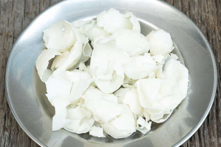 Eggshells in stainless steel dishes on a wooden table.の写真素材