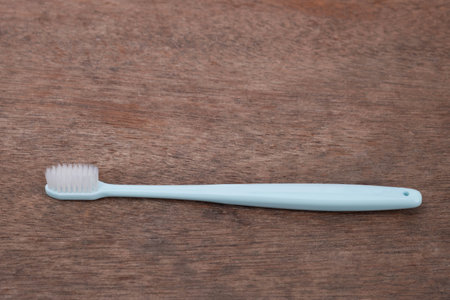 Soft-bristled toothbrush with blue handle on a dark brown wooden background. Concept of good oral...