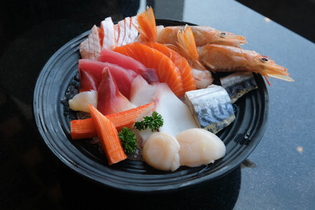 Raw fish set, Japanese food. Salmon, sweet shrimp, squid, clams, crab sticks, scallops, otoro in a black Japanese style plate.の写真素材