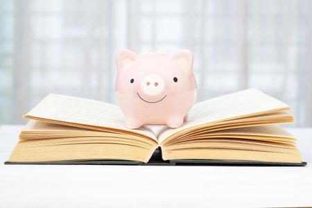 A pink piggy bank is placed on a book and beautiful blurred background. Concept of saving for education.の写真素材