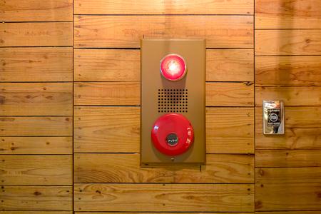 The pushing fire alarm on the wall next to the wall wood