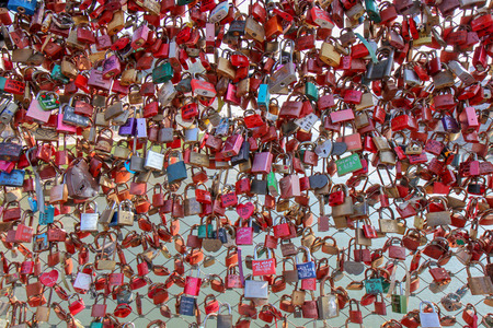 Closed fastened metal wedding locks fastened on bridge in of tourist attraction in Pedestrian Bridge...