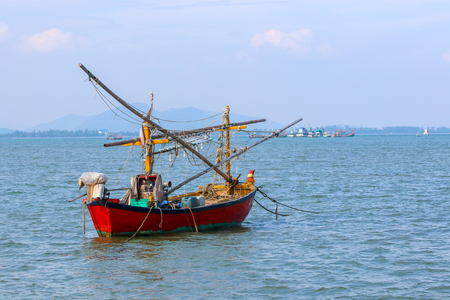 small fishing boat with fishing net and equipment  on water with mountain on backgroundの写真素材