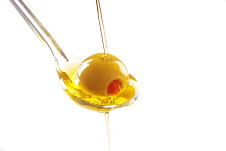 A spoon with an olive under a fall of oil の写真素材