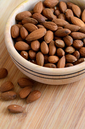 Raw peeled almond nuts in a woodel bowlの写真素材