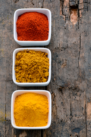 Hot red chili powder, curry and turmeric powder on wooden backgroundの写真素材