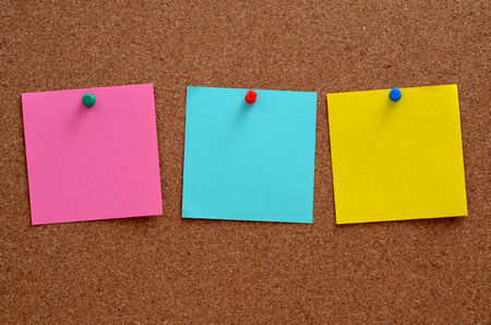 Blank, colourful notes pinned into brown corkboard
