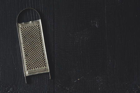 aged old rustic grater on a dark wooden table with copy spaceの写真素材