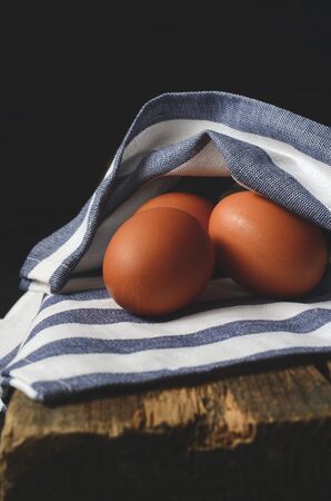 Chicken eggs on a dark wooden tableの写真素材